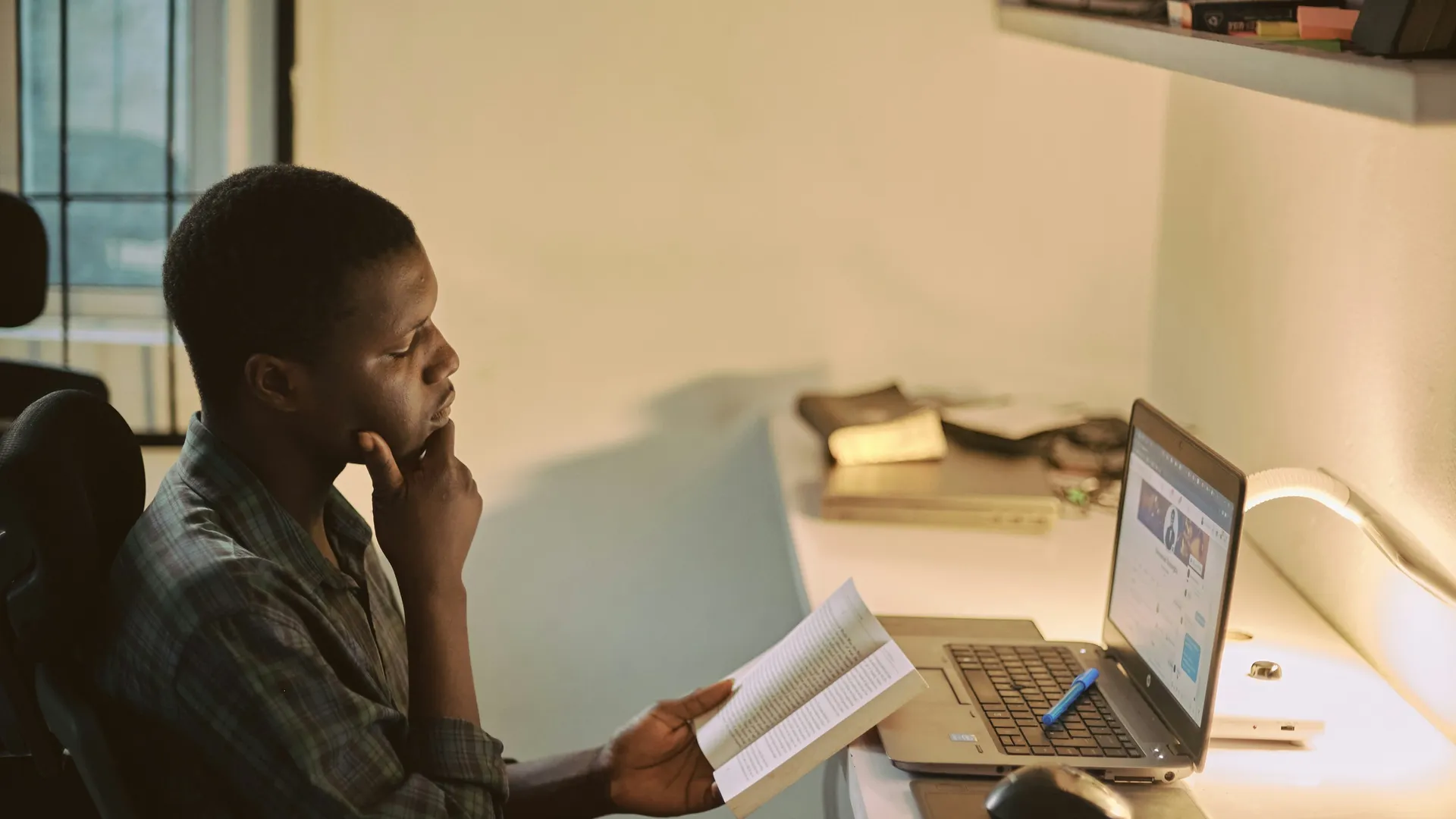 Student working with a book and laptop